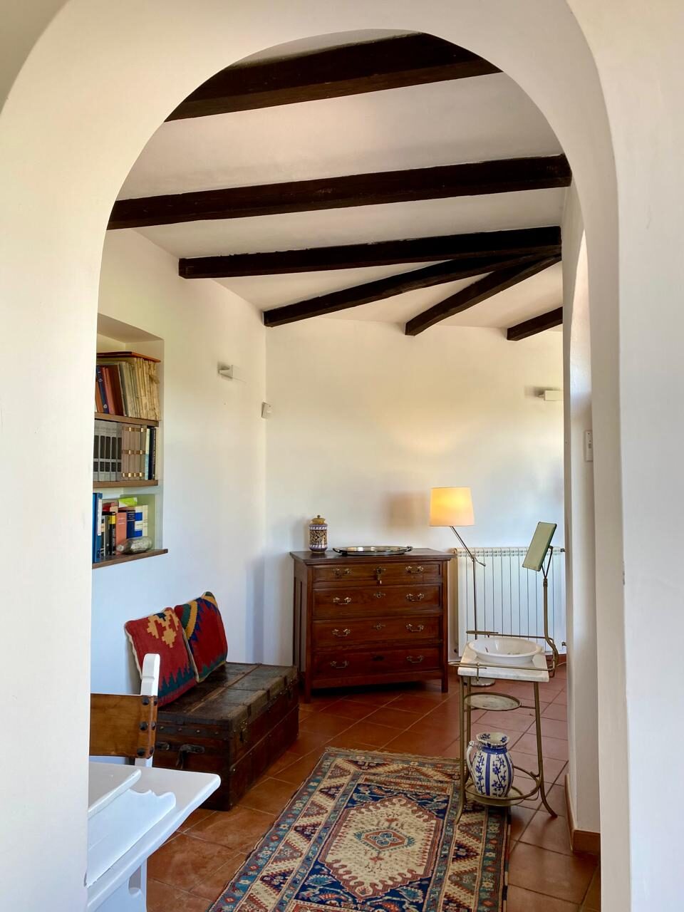 Arco con travi in legno, cassapanca antica e tappeto, interni della villa