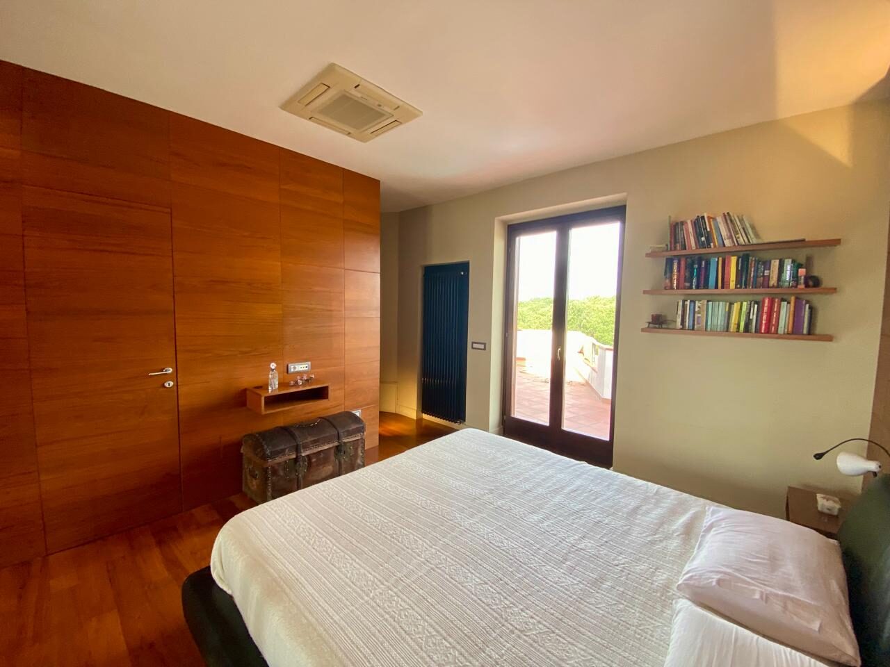 Camera in legno con porta-finestra sulla terrazza e libreria