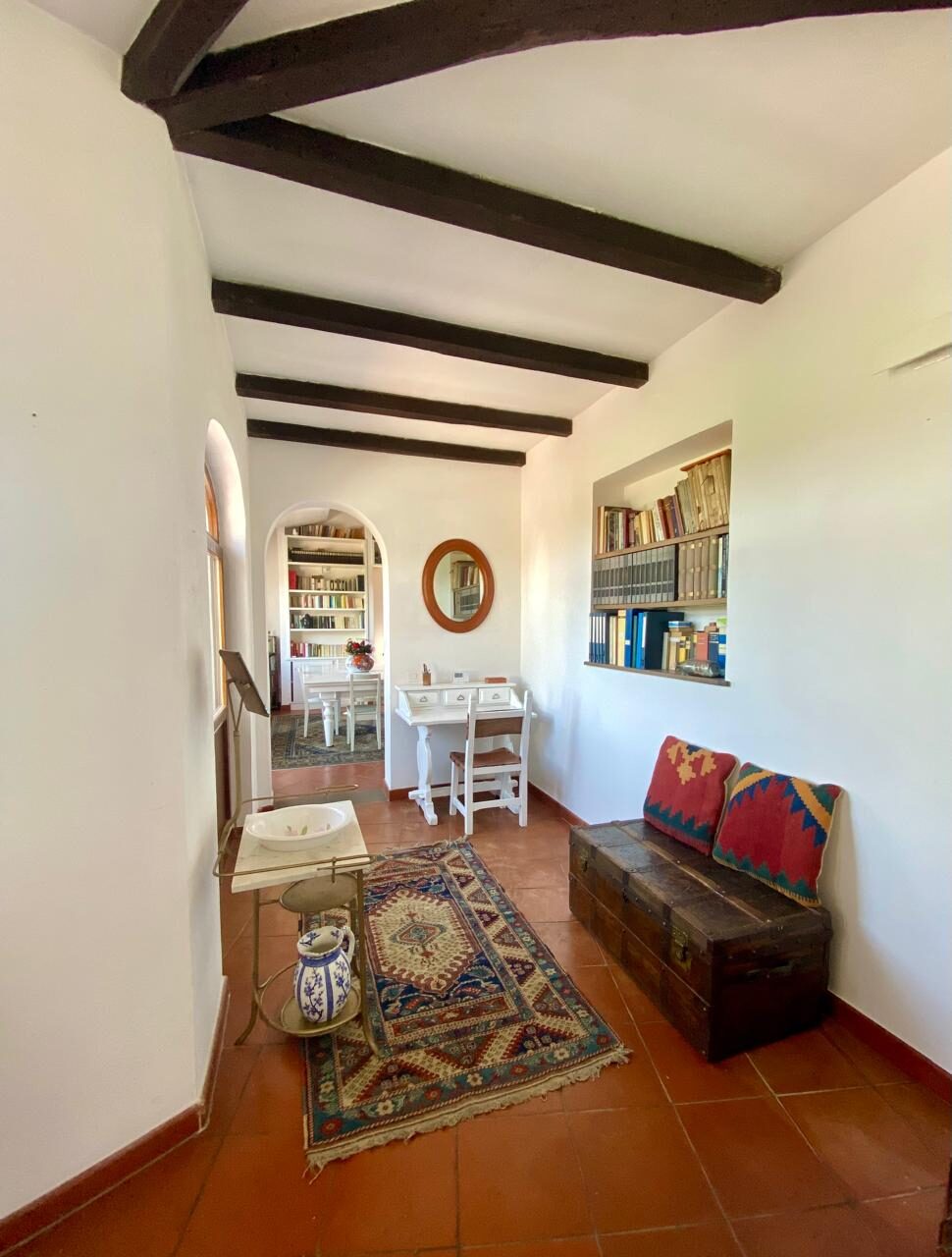 Corridoio con travi a vista, libreria e panca con cuscini kilim