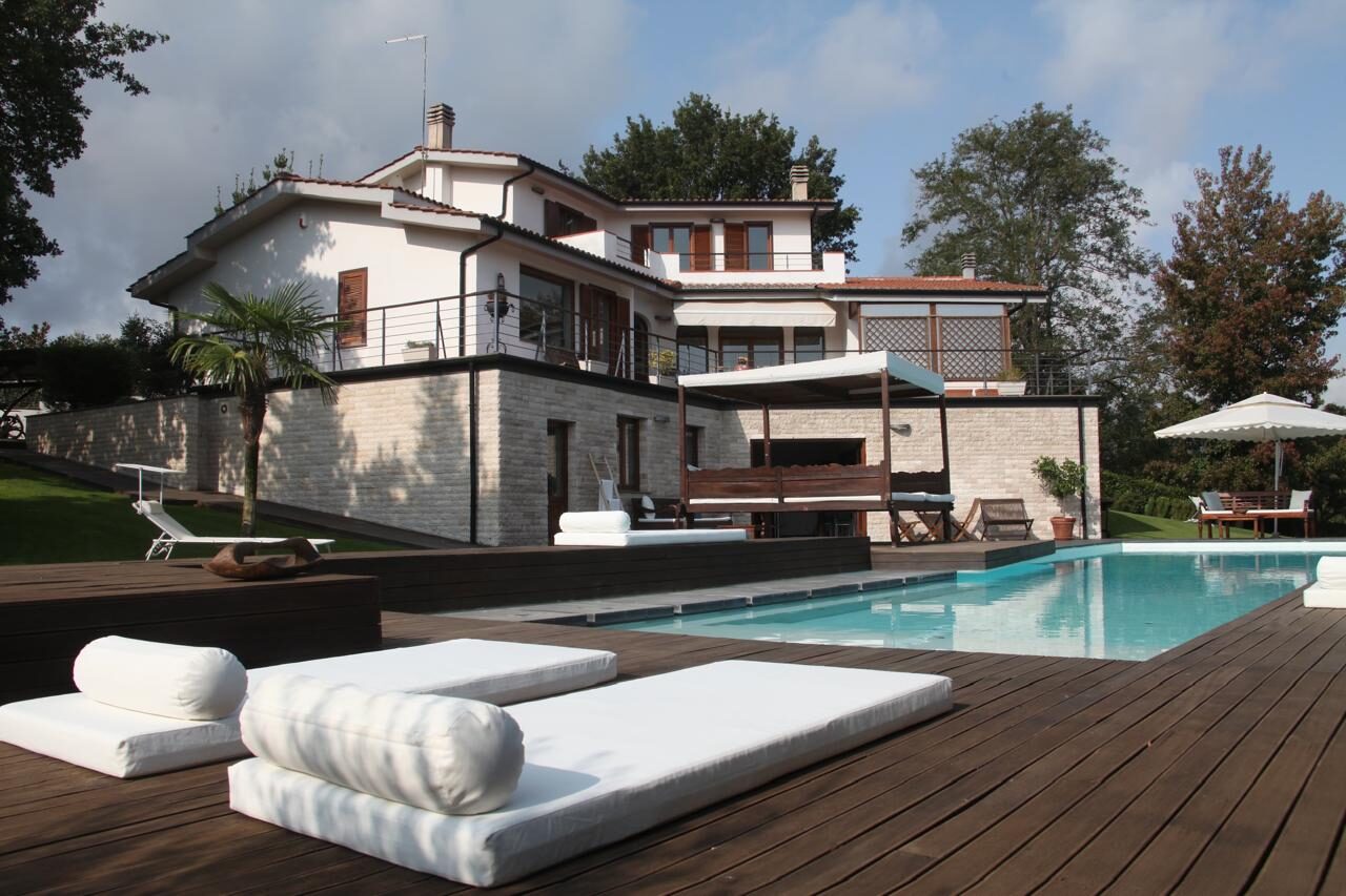 Lettini bianchi sul deck in legno della piscina, Villa Coccinella Lazio
