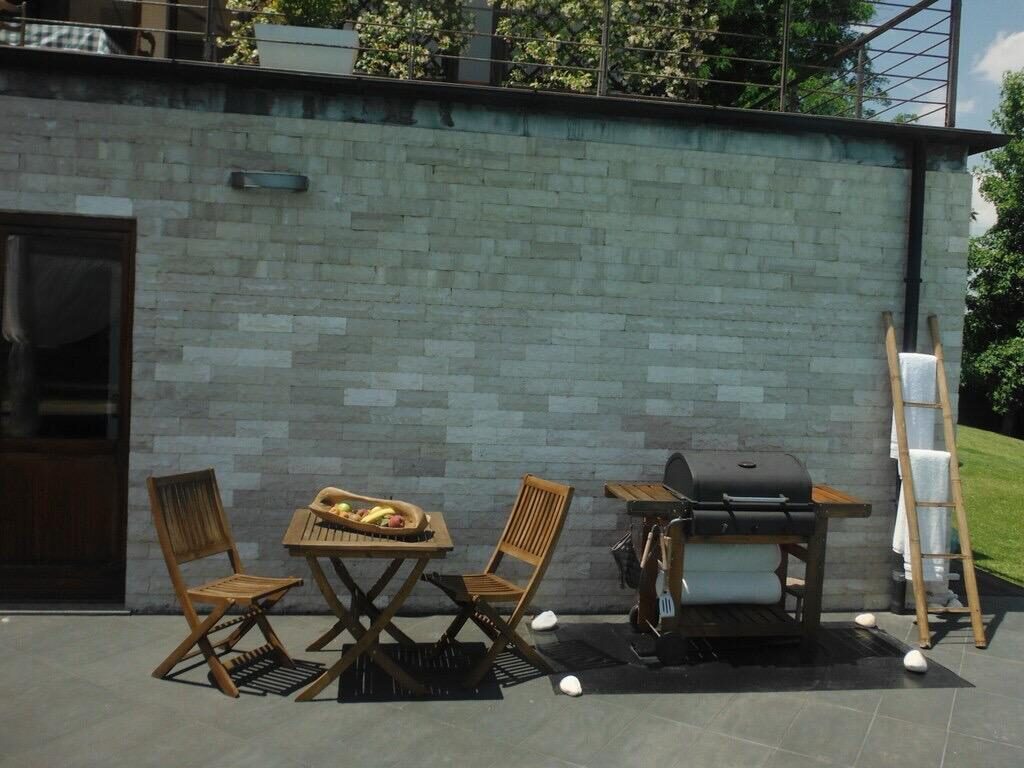 Tavolino in teak e barbecue a gas sul patio della villa a Nepi