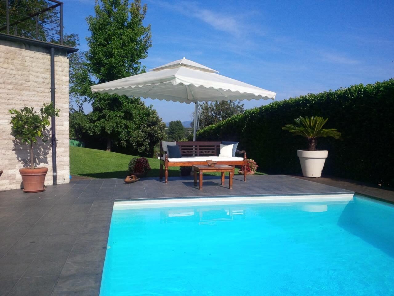 Piscina con ombrellone e salotto da esterno, villa con piscina vicino al lago di Bracciano